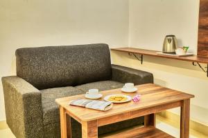 HOTEL VISA INN NEAR KEMPEGOWDA AIRPORT في بانغالور: غرفة معيشة مع كرسي وطاولة قهوة