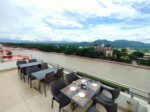 d'un balcon avec des tables et des chaises et une rivière. dans l'établissement Ganga Exotica, à Haridwar