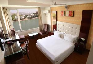 a bedroom with a white bed and a large window at Ganga Exotica in Haridwār