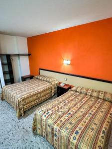 two beds in a hotel room with orange walls at Hotel Montreal in León