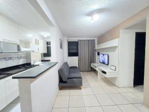 uma cozinha branca com uma cadeira e uma televisão em Apê UNIFA-EsSLog Condomínio com estacionamento no Rio de Janeiro