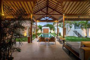 eine offene Terrasse mit einem Tisch, Stühlen und einem Pool in der Unterkunft House of Bagera by Alfred in Bali in Seminyak