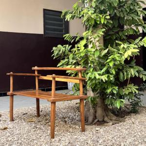 a wooden bench sitting next to a tree at Independent room on Island in colonial house with private entrance in Saint-Louis