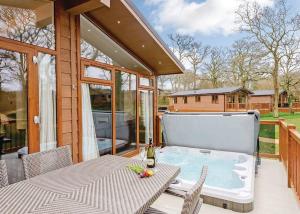 a hot tub on a patio with a table and chairs at Wareham Forest Lodge Retreat in Lytchett Minster