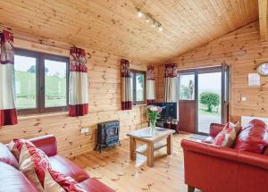 a living room with a red couch and a fireplace at Trewythen Lodges in Caersws