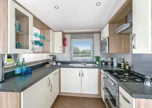 a kitchen with white cabinets and a stove top oven at Sunbeach Holiday Park in Llwyngwril