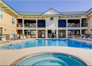 una piscina en un hotel con sillas y un edificio en Coligny Beach, Pools, & Shops- Few Steps Away, en Hilton Head Island