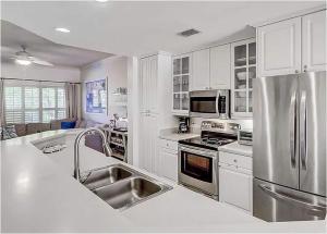 una cocina con armarios blancos y electrodomésticos de acero inoxidable en Coligny Beach, Pools, & Shops- Few Steps Away, en Hilton Head Island
