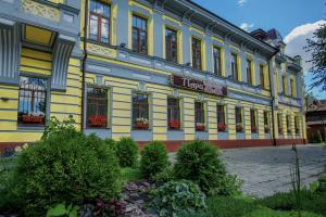 a yellow and blue building with flowers in front of it at Selivanov Hotel in Rostov