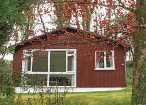 a red house with white windows and a tree at Ruthern Valley Holidays in Lanivet