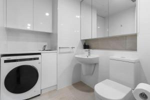 uma casa de banho branca com uma máquina de lavar roupa e um lavatório em Regent Residence on Collins with Free WiFi em Melbourne