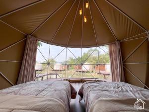 two beds in a tent with a large window at Eco Eyes Village in Nakhon Nayok