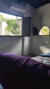 a bedroom with a purple bed and a window at Donde Polo Hostal in Suchitoto