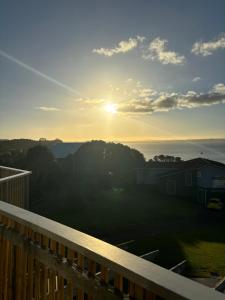 uma vista para o pôr-do-sol a partir do deque de uma casa em Sea View Apartment em Whangaparaoa