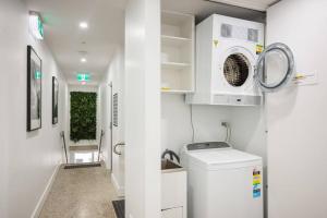 een kleine witte wasruimte met een wasmachine en droger bij NEW! Ideal 1BR Unit in the Hot Spot of Surry Hills in Sydney