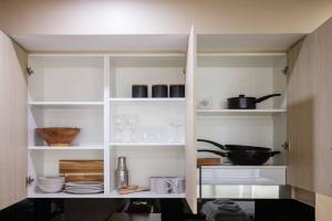 a pantry with white shelves with dishes and utensils at NEW! Ideal 1BR Unit in the Hot Spot of Surry Hills in Sydney