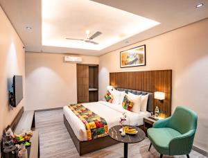 a hotel room with a bed and a green chair at Regenta Place Raaj Agra in Agra