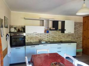 een keuken met witte kasten en een tafel met een rode tafellaken bij 2 bedrooms apartement with wifi at Livigno in Livigno