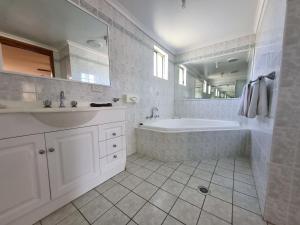 a white bathroom with a tub and a sink at Cardiff Motor Inn in Newcastle