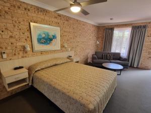 een slaapkamer met een bed, een bank en een tafel bij Cardiff Motor Inn in Newcastle