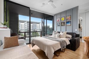 Brisbane Luxury Gabba Apartment في بريزبين: غرفة نوم بسريرين واريكة
