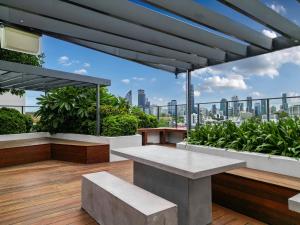 a rooftop patio with benches and a view of the city at Brisbane Luxury Gabba Apartment in Brisbane