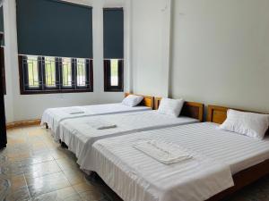 twee bedden in een kamer met twee ramen bij CHUNG BẰNG MOTEL in Hương Hóa