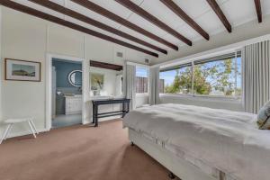 een slaapkamer met een bed, een raam en een bureau bij Long Point House in Merimbula