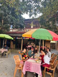 un grupo de personas sentadas en una mesa bajo un paraguas en Horizon Homes - Sauraha Chitwan, en Sauraha