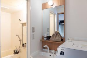 ein Bad mit einem Waschbecken und einem Spiegel in der Unterkunft yksi STAY ＆ APARTMENT OSAKA in Osaka