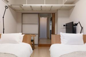1 dormitorio con 2 camas, escritorio y puerta en yksi STAY ＆ APARTMENT OSAKA, en Osaka