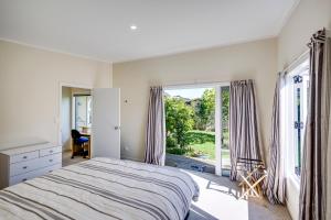 a bedroom with a bed and a large window at Garden Retreat - Napier Holiday Home in Napier