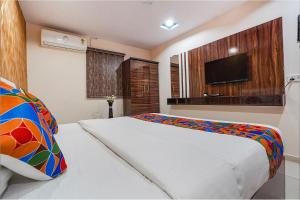 um quarto com uma cama branca e uma televisão em FabHotel Olive Stay Inn em Nagpur