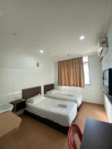 a hotel room with two beds and a table at UMMUL MOTEL CMART in Arau