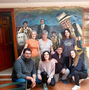 a group of people posing in front of a painting at Posada Todos Santos in Cuenca