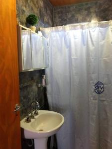 baño con lavabo y cortina de ducha blanca en Hospedaje La Ushuta Negra in 