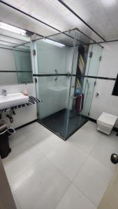 ムンバイにあるHome sweet home 3BHKのバスルーム(ガラス張りのシャワー、シンク付)