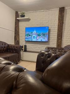 a living room with leather couches and a flat screen tv at History Hostel in Ouro Preto