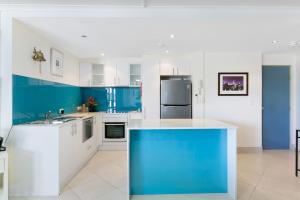 a blue and white kitchen with white and blue cabinets at Bright 2-Bed with Pool, Spa & Tennis Court in Gold Coast