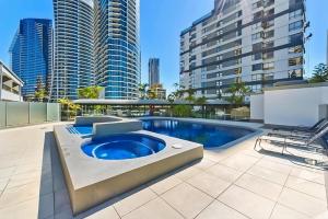 a pool on the roof of a building with tall buildings at Bright 2-Bed with Pool, Spa & Tennis Court in Gold Coast