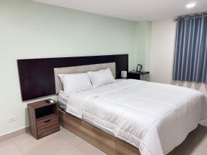 a bedroom with a large white bed with a wooden night stand at The Freelancer Hotel in Pattaya Central