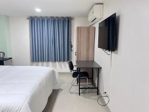 a bedroom with a bed and a desk and a television at The Freelancer Hotel in Pattaya Central