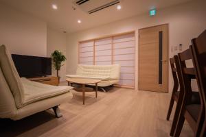 ein Wohnzimmer mit Stühlen, einem TV und einem Tisch in der Unterkunft Ryo An in Otaru