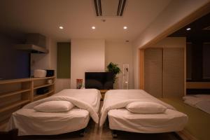 two twin beds in a room with a television at Ryo An in Otaru