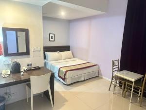 a bedroom with a bed and a desk and a table and chairs at KINGSMAN BOUTIQUE HOTEL in Kota Kinabalu