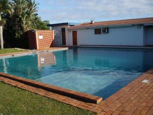 a swimming pool with blue water in front of a house at Sea Fever Lodge in Umkomaas