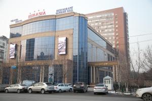 un gran edificio de cristal con coches estacionados frente a él en Grand Hotel Eurasia, en Almaty