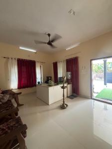 uma sala de estar com uma ventoinha de tecto e cortinas vermelhas em Anugraha Lotus Homestay em Varkala
