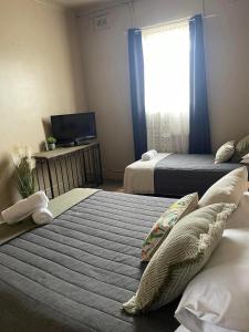 Quirindi的住宿－Federal Hotel，一间卧室设有两张床、一台电视和一扇窗户。