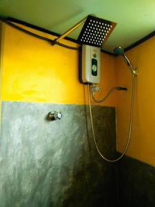 y baño con ducha y pared amarilla. en Rainforest View, en Deniyaya